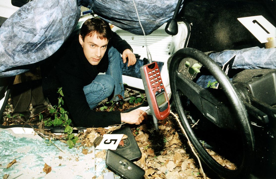 Kommissar Brandtner (Gedeon Burkhard) nimmt das Autowrack etwas genauer unter die Lupe. Er entdeckt ein Mobiltelefon. Hat die Verunglückte kurz vor... - Bildquelle: Ali Schafler Sat.1